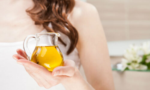 foto en closeup de la mano de mujer blanca con un aceitera de cristal.